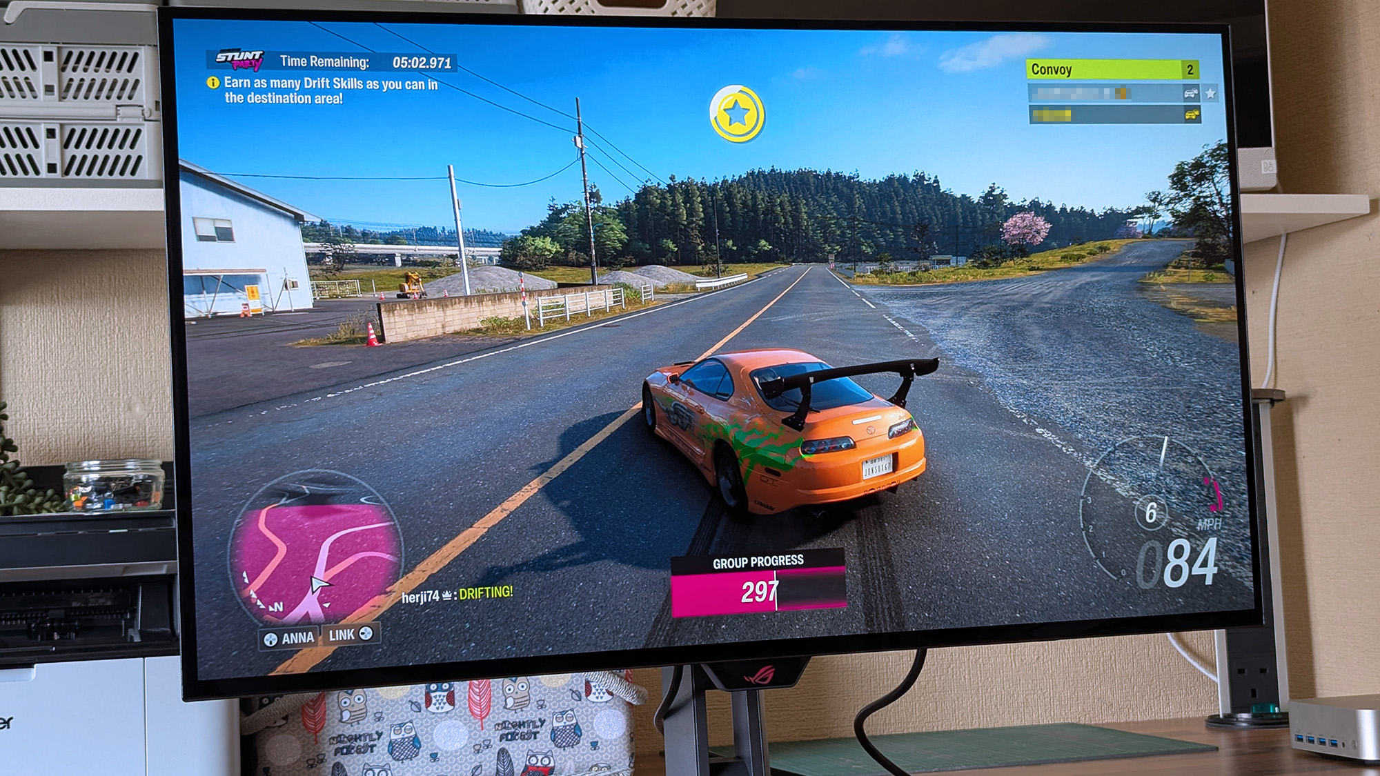 ASUS ROG Strix OLED XG32UQWMS monitor displays Forza Horizon 6 racing with an orange sports car drifting on a rural road, showing timers, drift objectives, convoy players, and speed indicators.