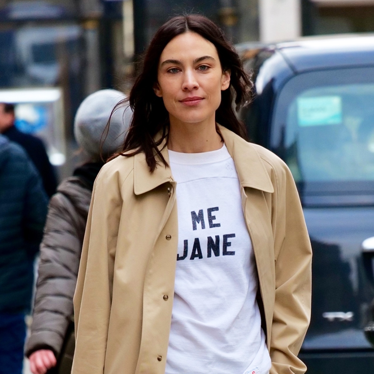 Alexa Chung wearing a trench coat, white T-shirt, army green utility pants, and metallic pink kitten heels in London