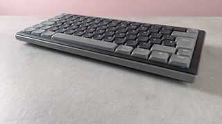 Cherry XTRFY K63W Pro Compact Ultra-Wideband on desk with pink wall in background