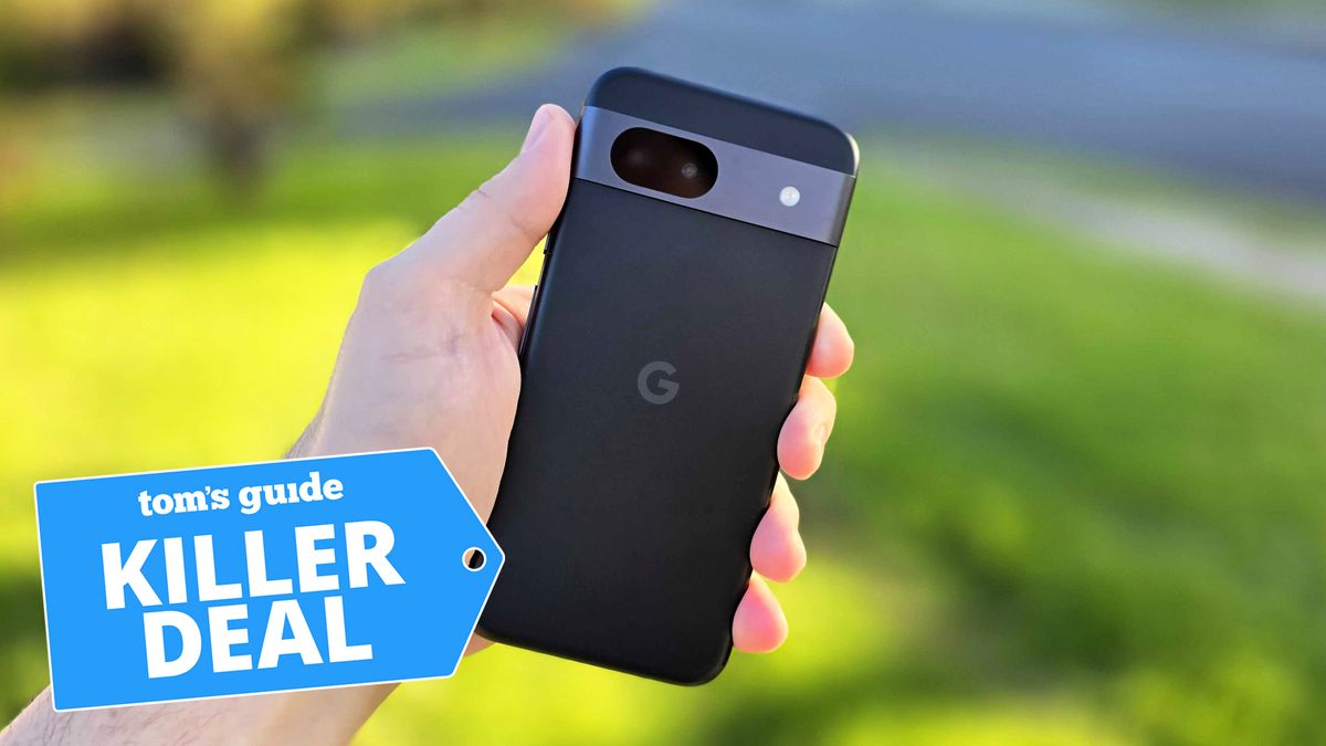 In-hand photo of the black Google Pixel 8a handset in front of outdoor setting with &#039;Killer Deal&#039; badge overlaid.