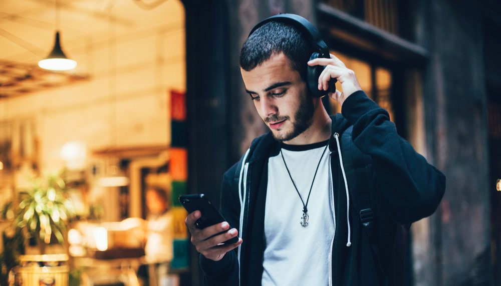 A young man listening to music through wireless headphones.