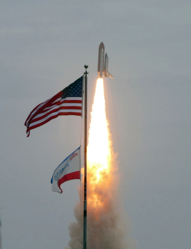 atlantis flies past flags