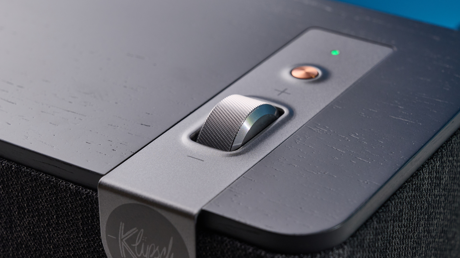 Klipsch The One Plus Bluetooth speaker in matte black photographed in front of a blue background.
