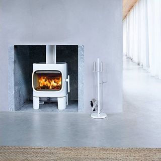 Fire in woodburning stove set in enclosed fireplace set with grey walls and floor