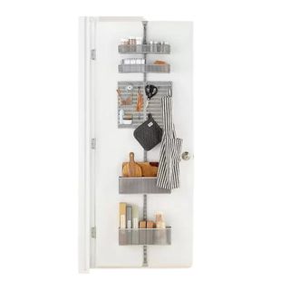 The Elfa utility wire rack with baskets and pegboards holding kitchen essentials including chopping boards, food wrap, condiments, oven gloves and apron