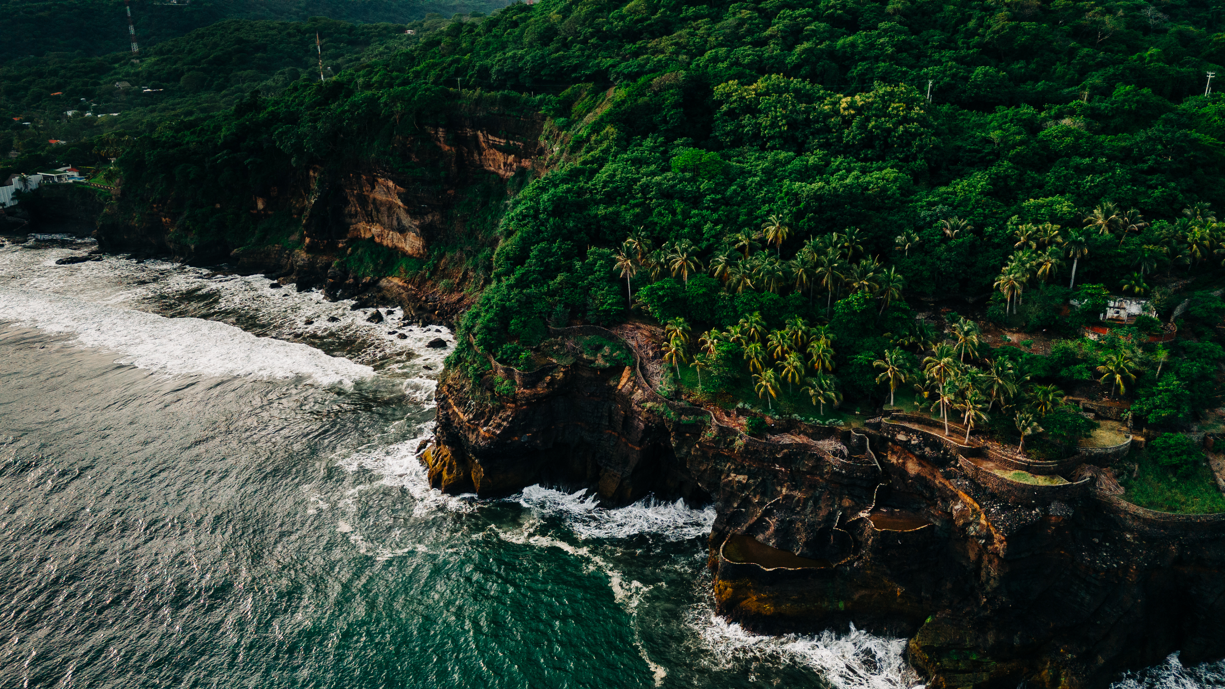 An aerial view of the lush green cliffs above the ocean in El Zonte, El Salvador