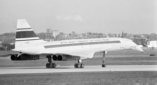 Concorde lands after successful flight, with mechanism in tail showing parachute has been deployed and released from rear of aircraft.