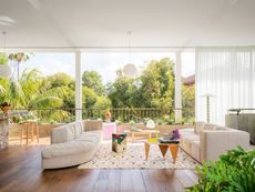 Living area with expansive sliding doors to terrace, with curved sofas and pointed coffee table