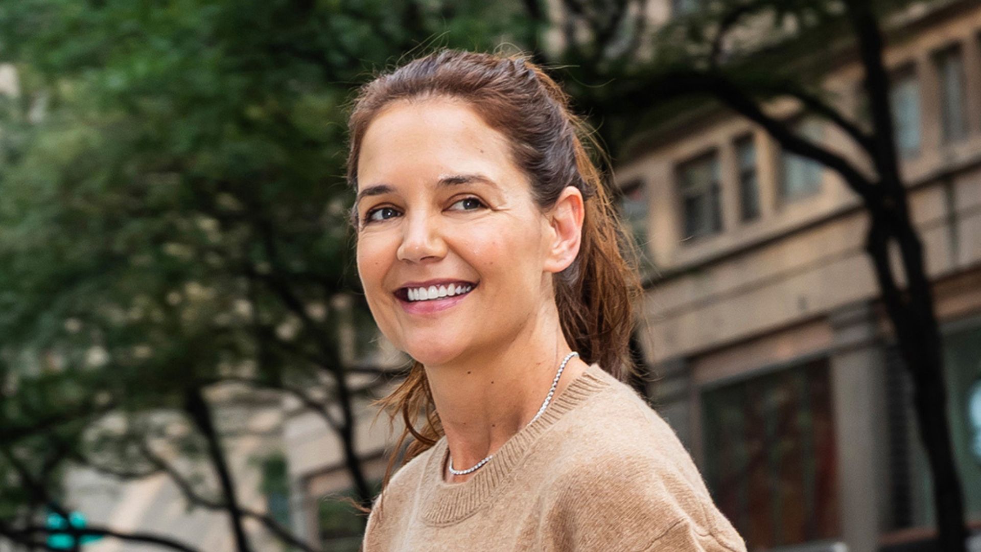 Katie Holmes wearing midi skirt, knit jumper and loafers on 23 September, 2025