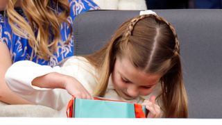 Princess Charlotte of Cambridge opens her Fortnum & Mason gift bag as she attends the Platinum Pageant on The Mall on June 5, 2022 in London, England
