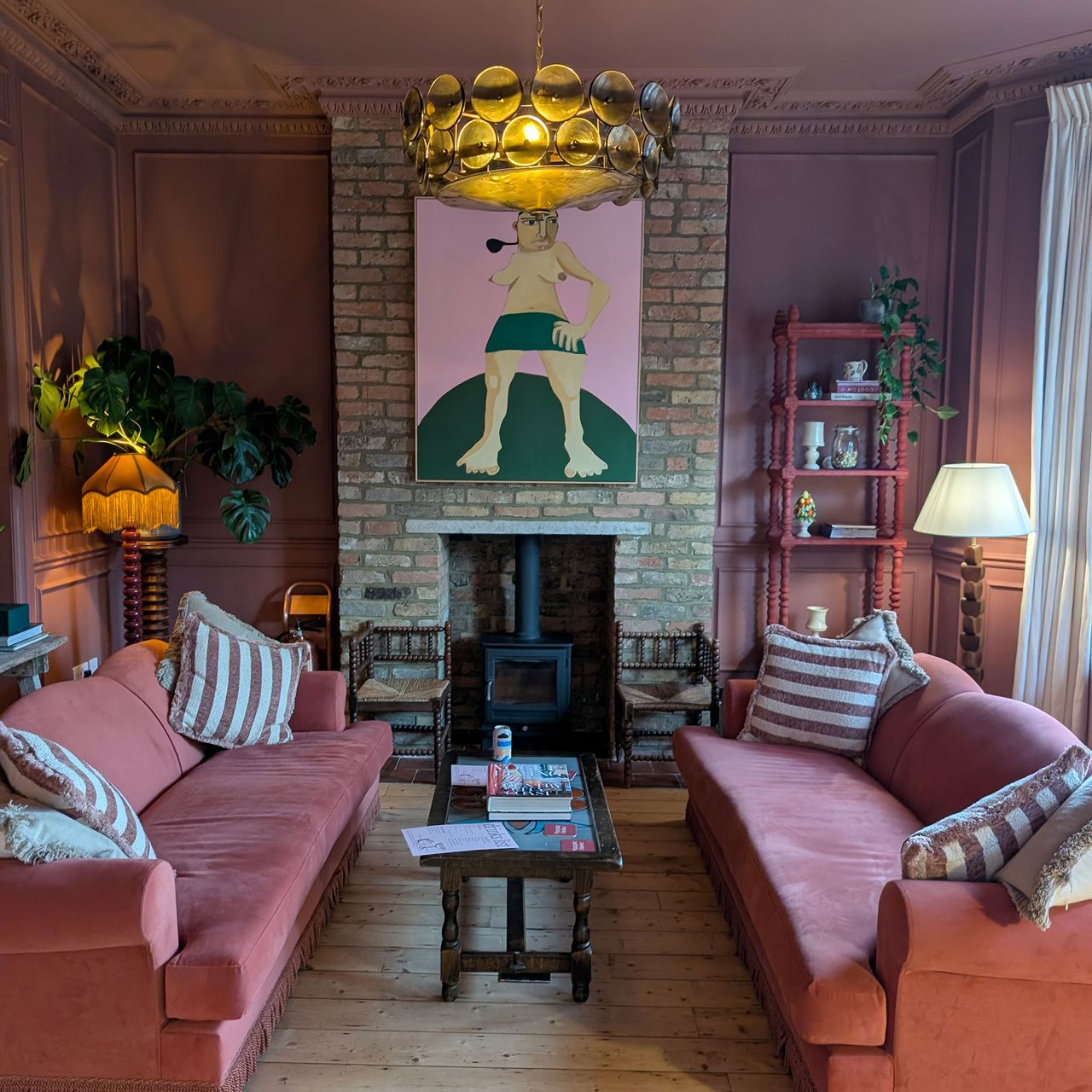 Living room with two red sofas facing each other across slimline wooden coffee table in front of of brick covered fireplace area