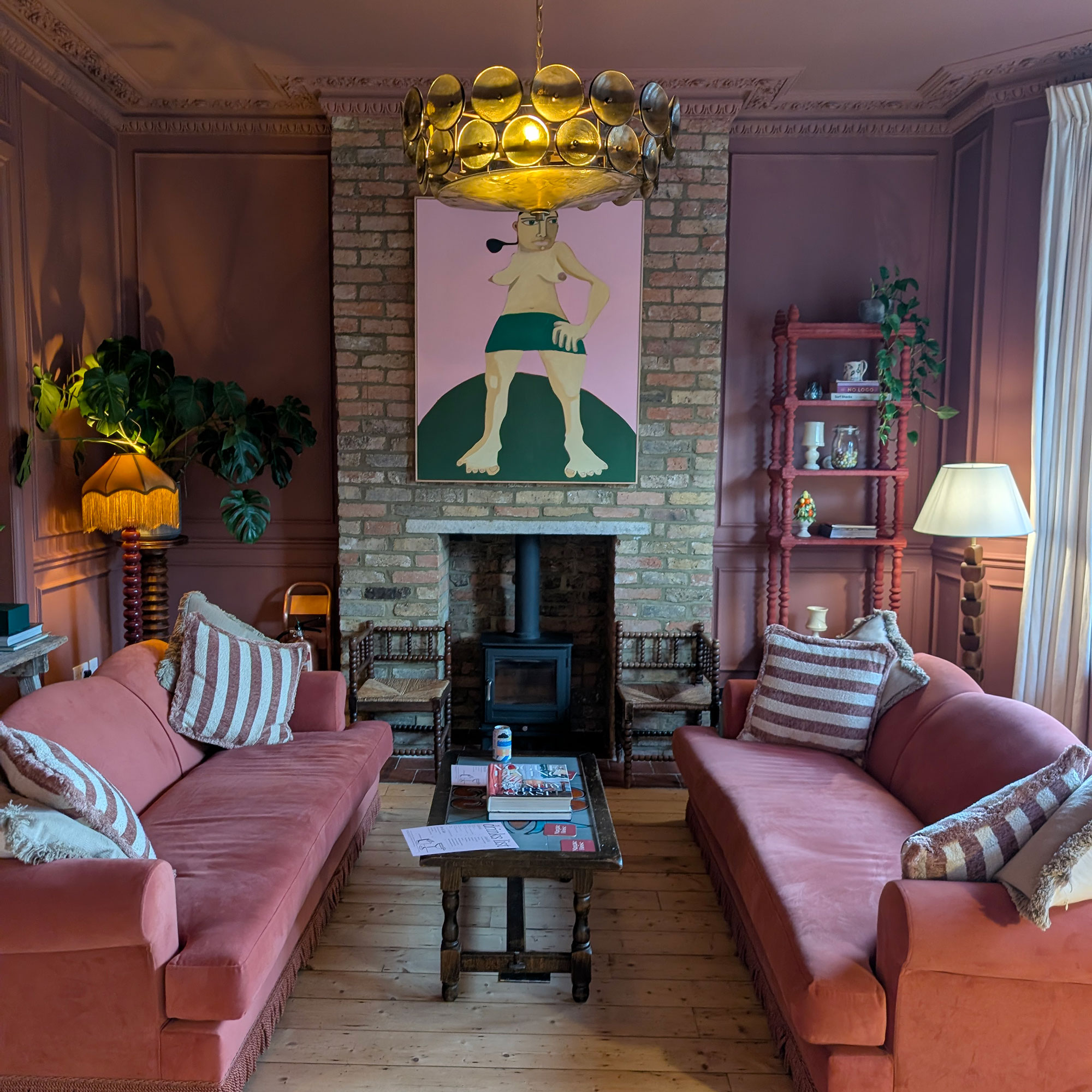 Living room with two red sofas facing each other across slimline wooden coffee table in front of of brick covered fireplace area