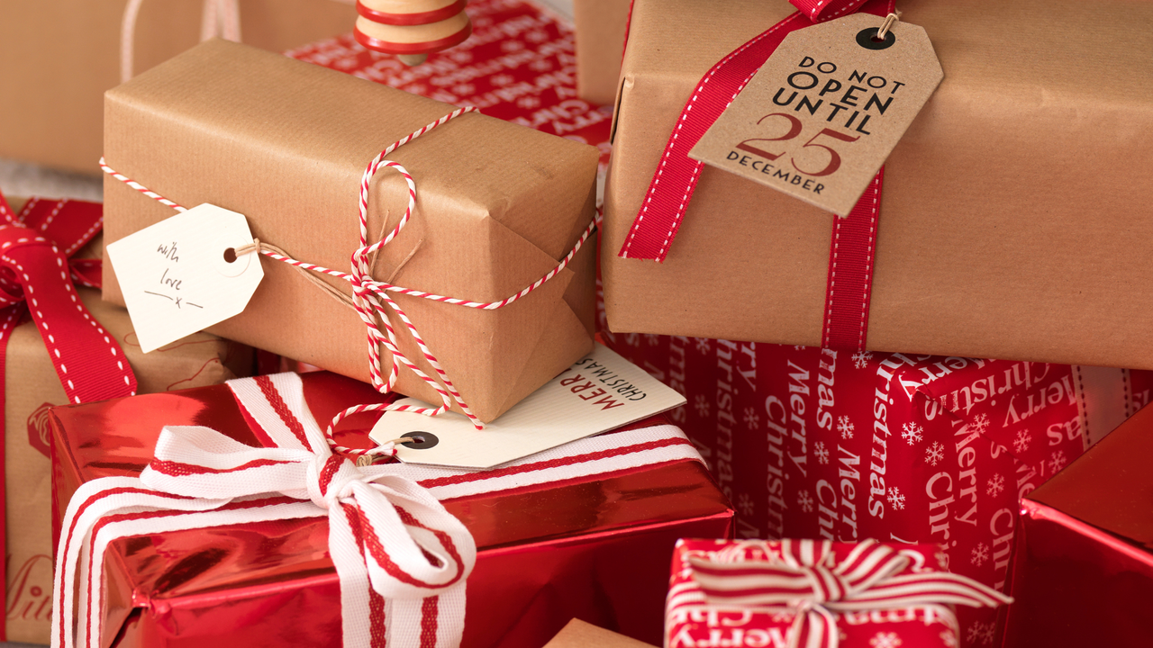 Closeup of Christmas presents under tree wrapped in red and brown paper.