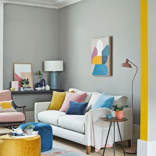 grey living room with a cream colored sofa and colorful pillows decorated with a wooden table topped with accessories