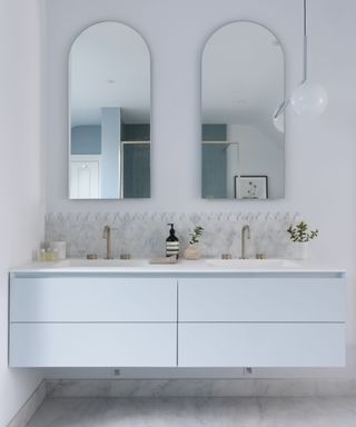 A blue, white and gray bathroom with a floating vanity and marble tiles