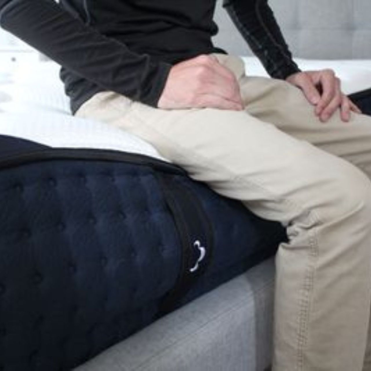 Man sits on edge of DreamCloud Luxury Hybrid Mattress.