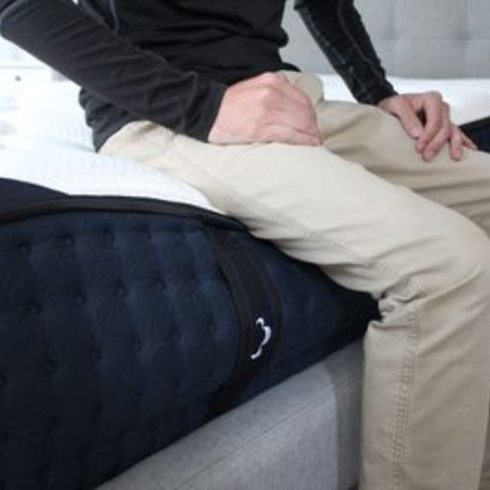Man sits on edge of DreamCloud Luxury Hybrid Mattress.