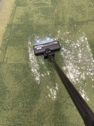 Tineco Pure One Station vacuuming flour and sugar on green carpet