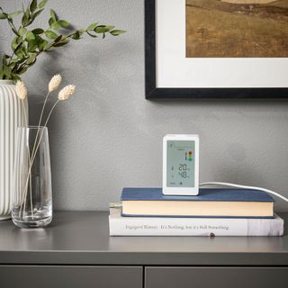 an IKEA air quality monitor on a sideboard on top of a pile of books