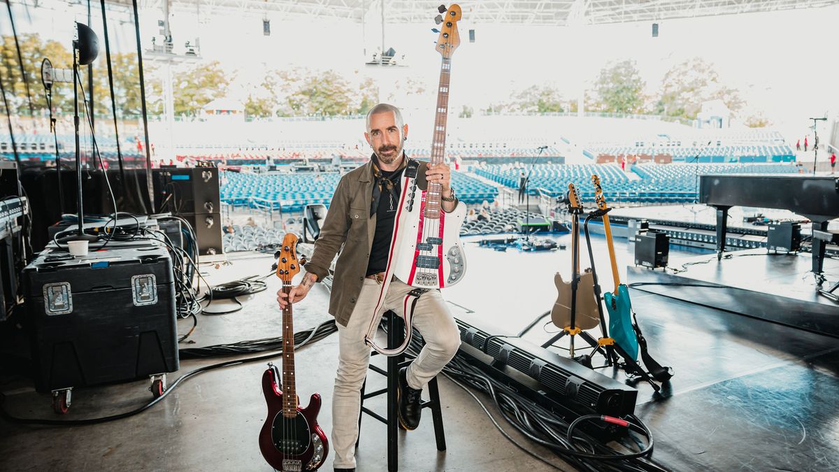 Derek Frank poses with Fender and Ernie Ball Music Man bass guitars