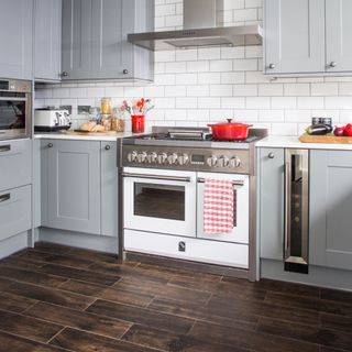 Kitchen with grey cabinets, white worktops, and dark wood effect flooring