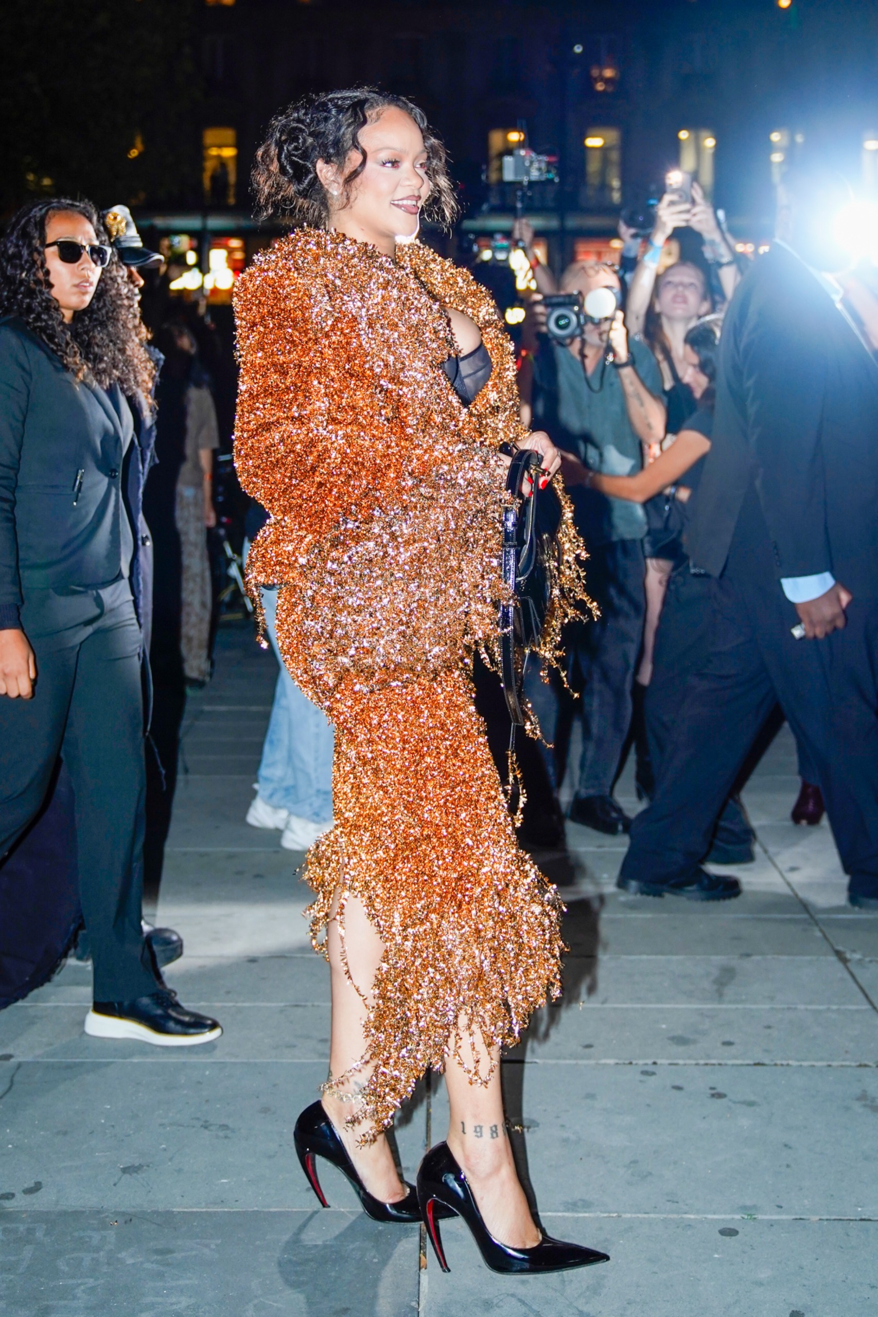 Rihanna attends Mati&amp;egrave;res F&amp;eacute;cales's Spring/Summer 2027 show at Paris Fashion Week, wearing a glittery orange matching set and a peekaboo bra