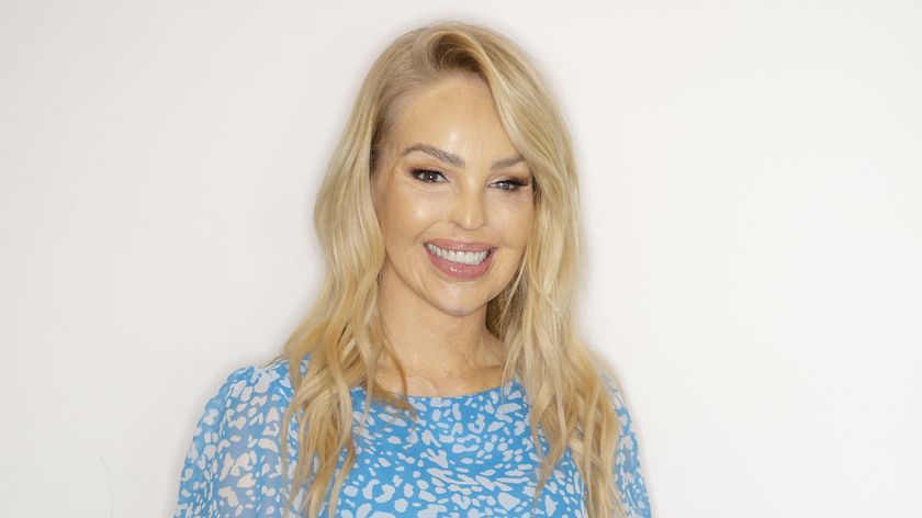 Katie with her blonde hair down and wearing a blue and white patterned dress, smiling for the camera. 