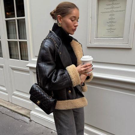 Woman wearing a black shearling coat, jeans, and a Chanel bag