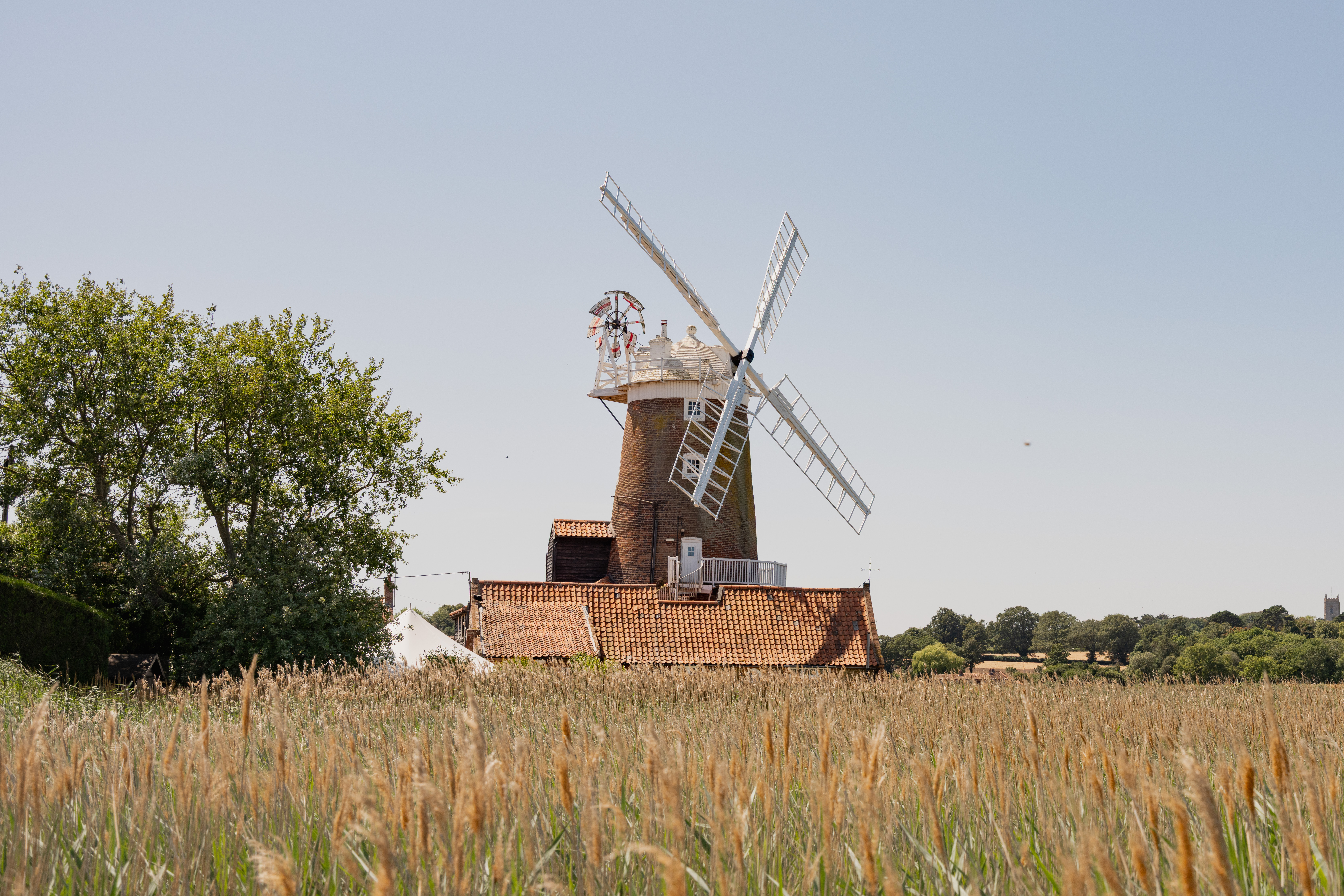 Cley Windmill. The mill is surrounded by reed beds and little rivers, and it is red brick with a white top. Inside, the rooms are luxurious but rustic, with lots of brick and exposed beams.