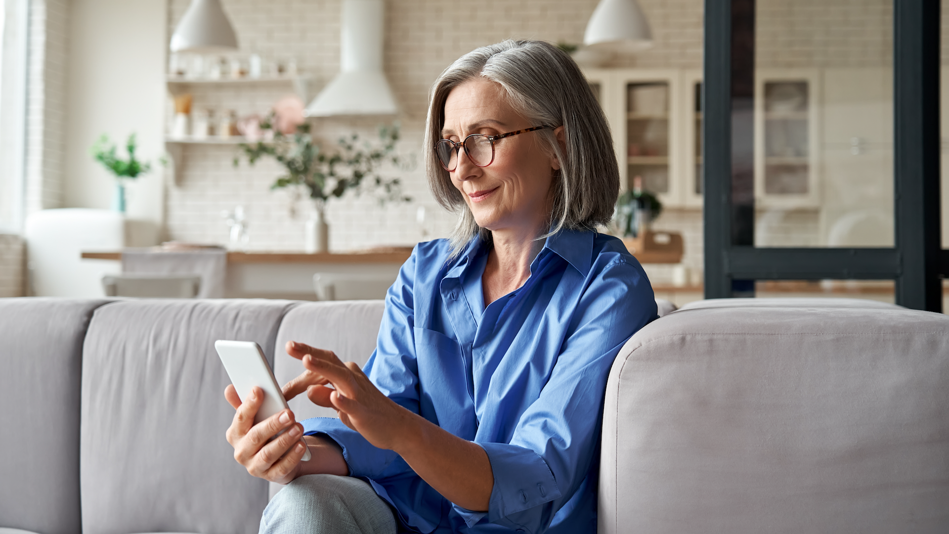 Woman looking at phone while sat on sofa