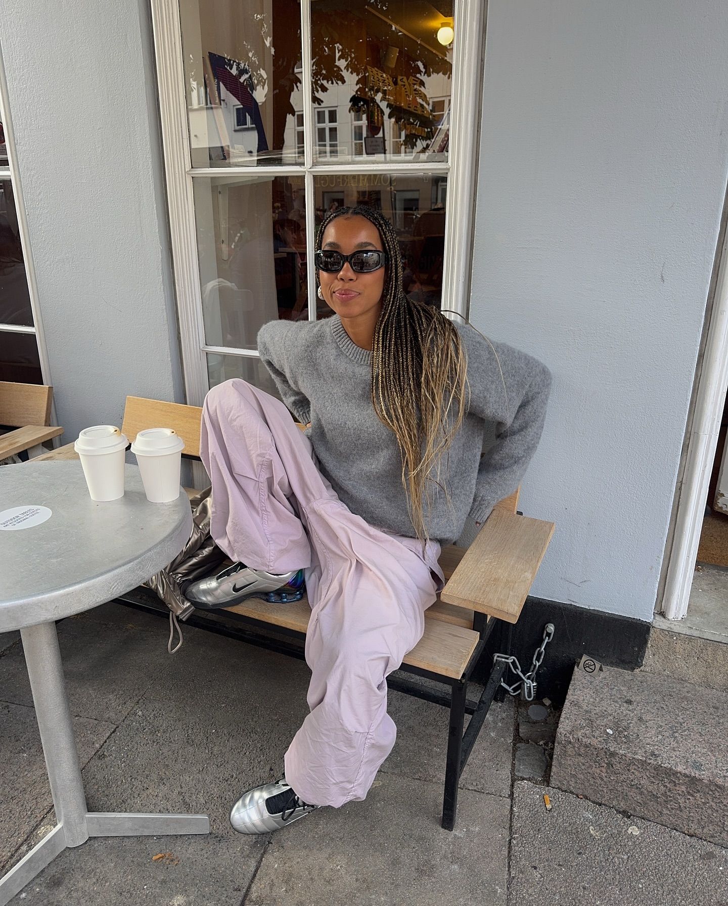 An image of @amaka.hamelijnck wearing a grey jumper with pink balloon trousers and metallic trainers from Nike.