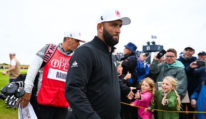 Jon Rahm high fives fans as he walks off the green