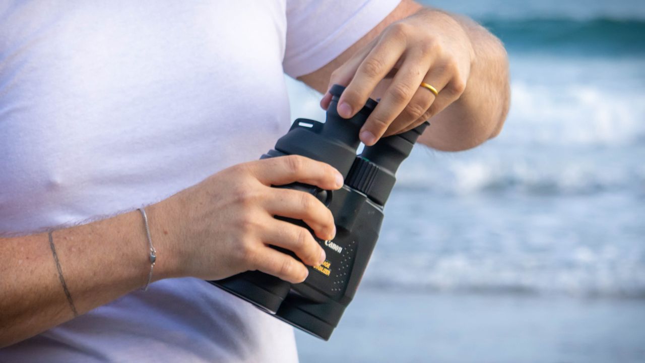 A close up of someone demonstrating the eyecup positions on the Canon 18x50 IS binoculars.