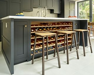 Dark kitchen island with integrated wine storage and industrial style bar stools