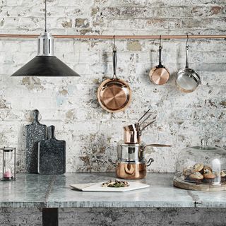 kitchen area with frying pans on exposed brick walls