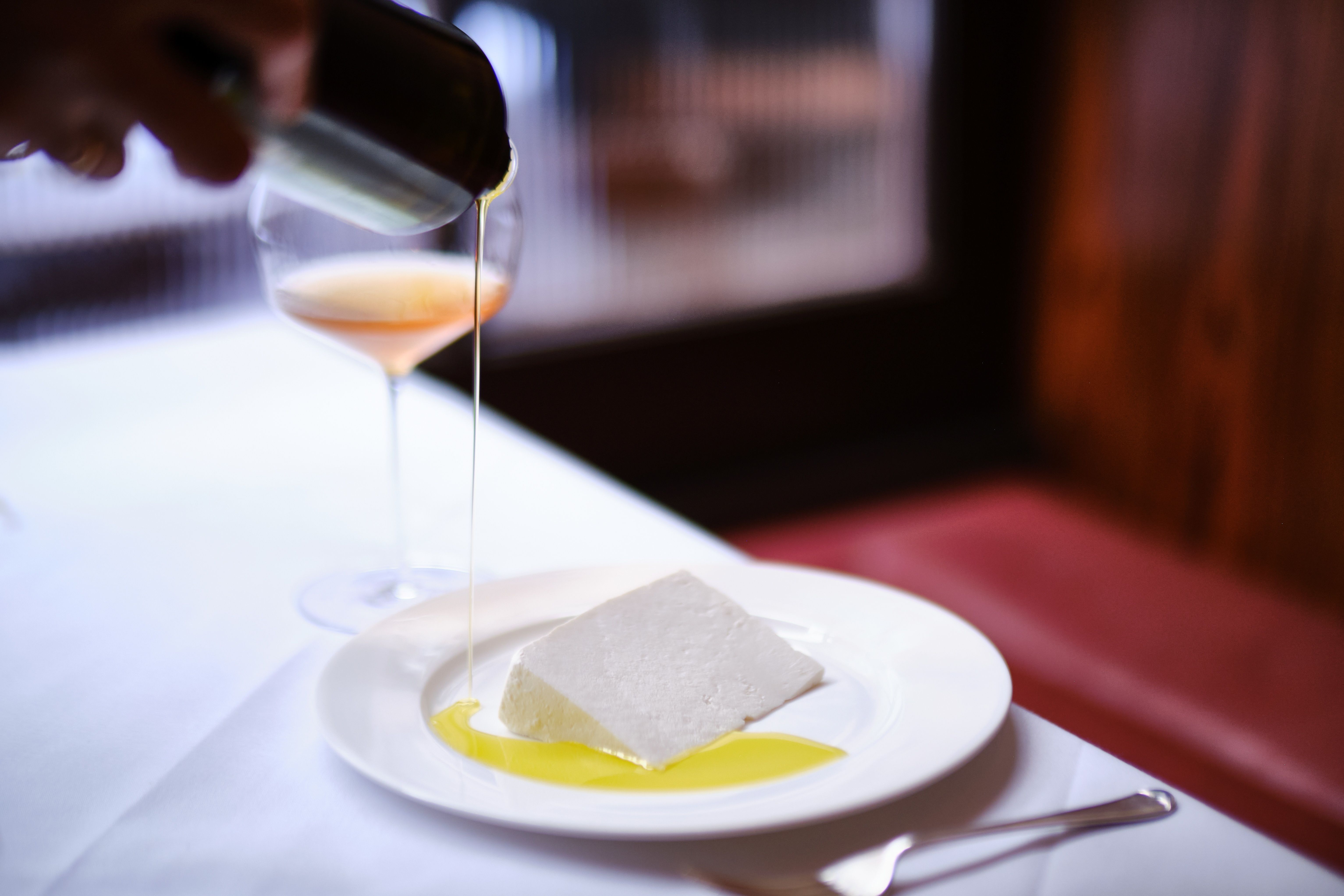 A series of interior shots of a restaurant lit with candles and decorated with traditional serveware, framed wooden paintings, and wooden detailing.