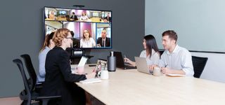 Four people sat around a table, video conferencing with others.