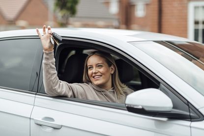 Woman leaning out of a car window holding a set of car keys