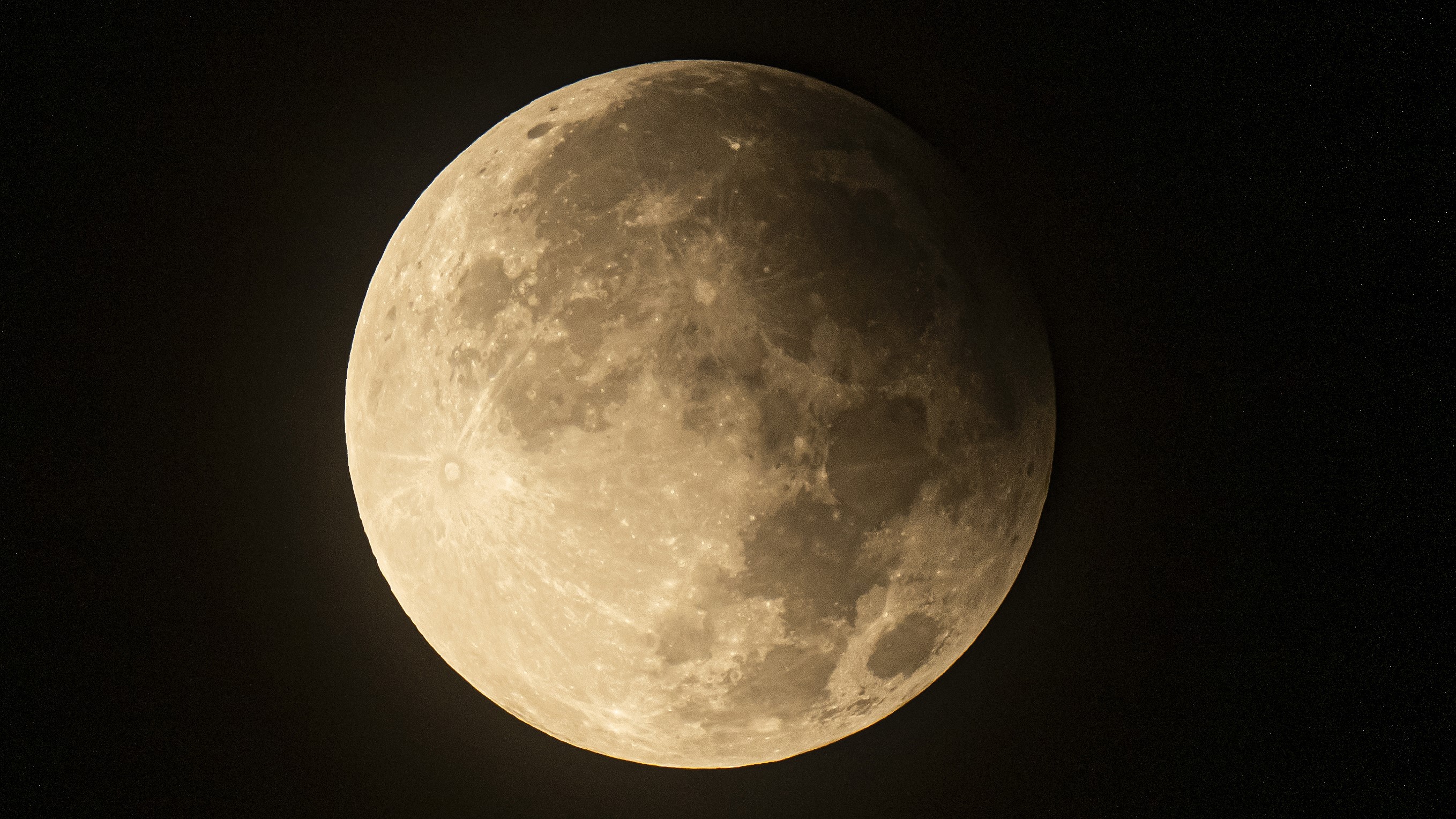 a close-up of the entire lunar disk with part of the moon in the shadow of the earth during the lunar eclipse.