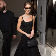 Bella Hadid wears a black drop-waist dress.