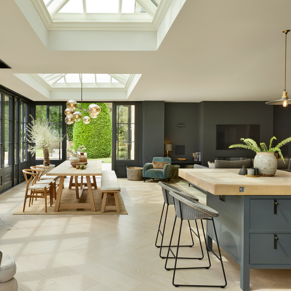 A modern kitchen with exposed brick and surround black framed conservatory windows