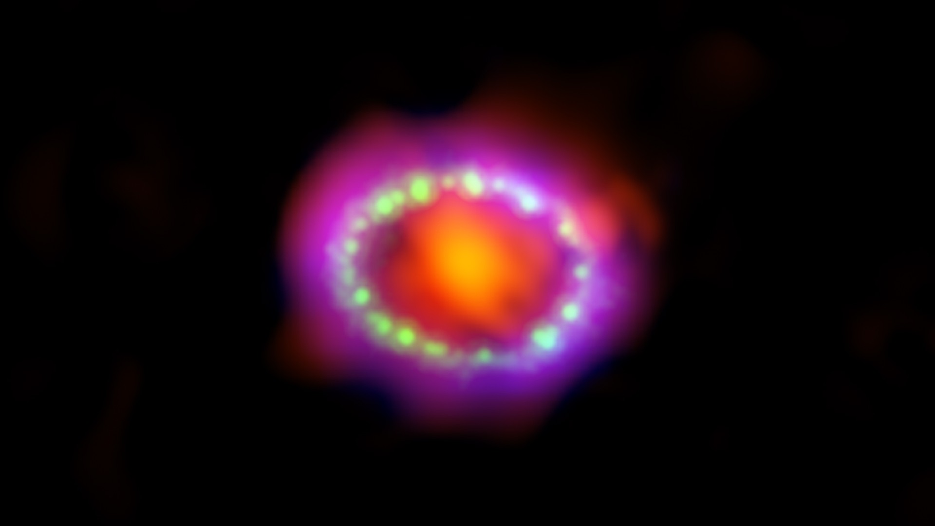 Image of SN 1987A, the brightest supernova in more than 400 years. Here we see an orange-red circular center surrounded by white dots, then a purple and red ring.
