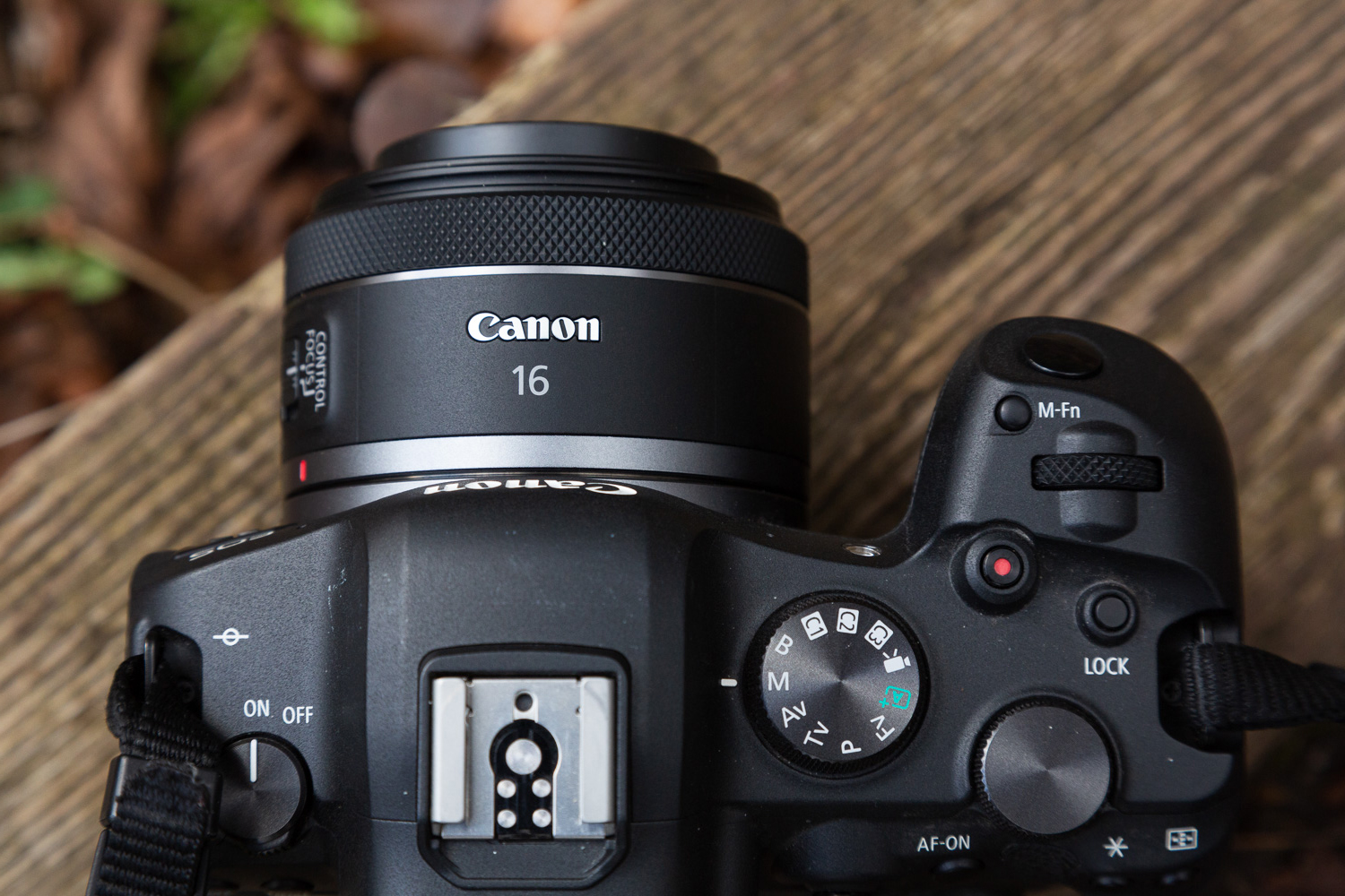 A Canon camera with lens on a wooden block