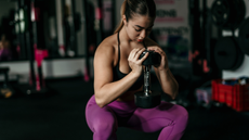 A woman performing cyclist squat with dumbbell