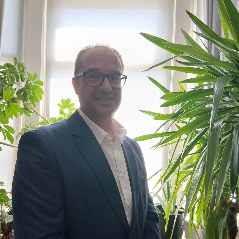 male stood in front of window next to plants