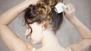 woman brushing scalp with hairbrush, to signify scalp massage for hair growth