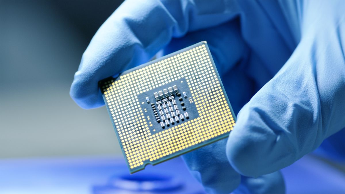 A processor chip being held in a gloved hand