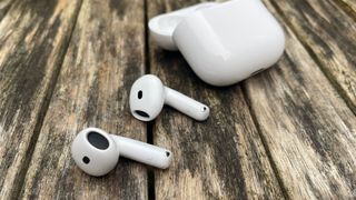 Apple AirPods 4 with ANC wireless earbuds and case on wooden table