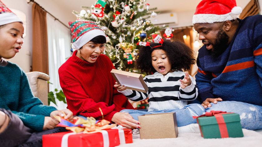 A family opening presents while wearing festive hats in front of a lit up tree.