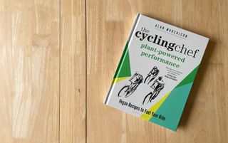 A copy of The Cycling Chef Plant-Powered Performance on a light wooden work surface